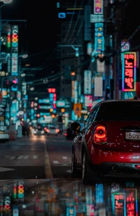 Vibrant Nightlife: A Compact Car Amidst Neon-Lit Urban Streets