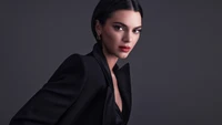 Kendall Jenner en elegante conjunto negro contra fondo oscuro