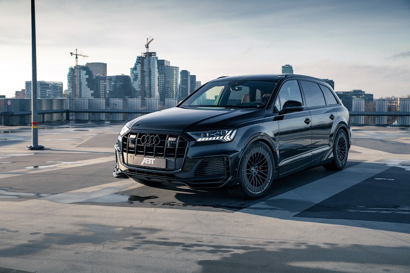 Черный ауди внедорожник припаркован на парковке с городом на фоне (abt audi sq7 tfsi widebody, черные автомобили, 2021, машины, обои 4k)