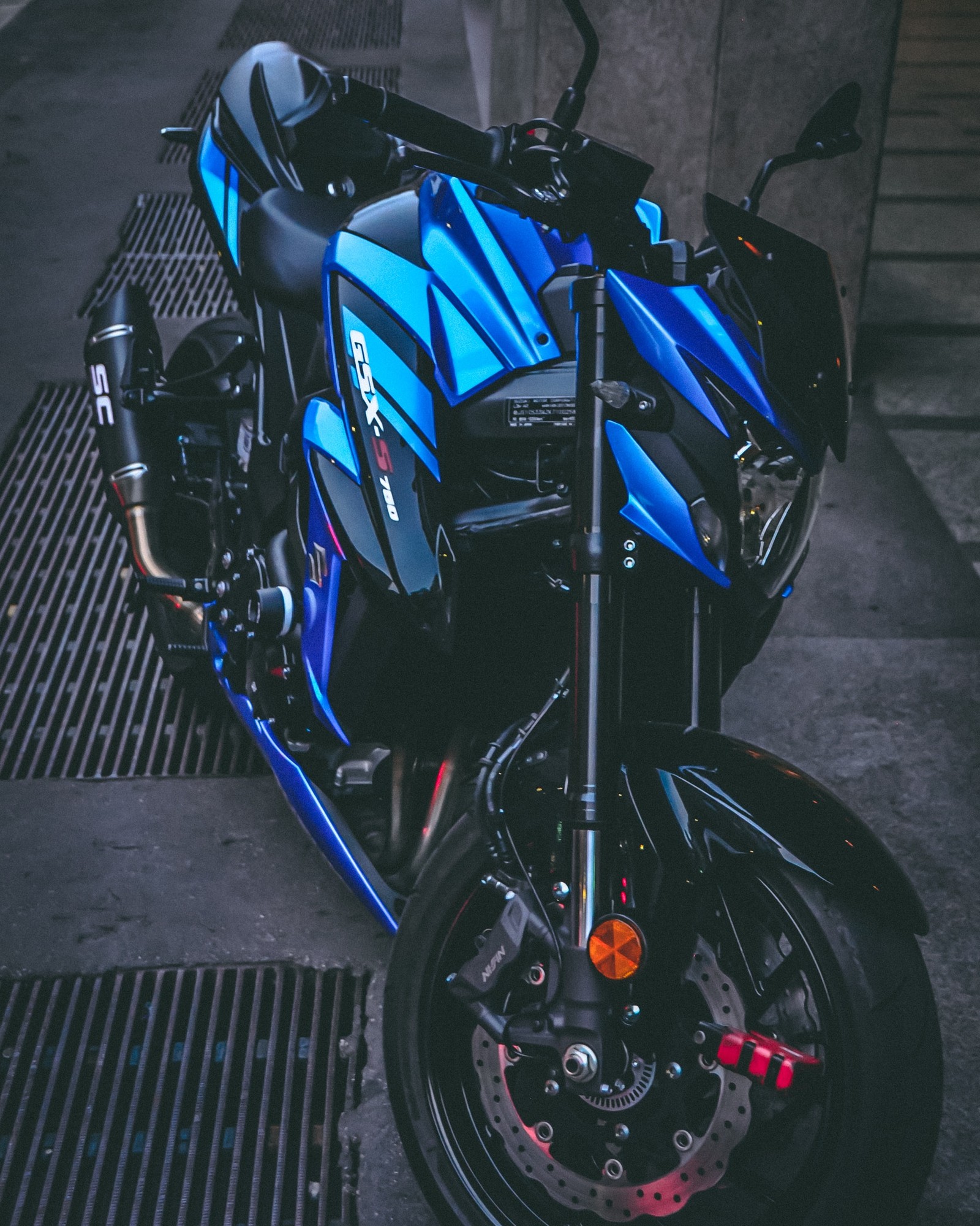 A close up of a motorcycle parked on a sidewalk near a building (motorcycle, tire, automotive tire, rim, wheel)