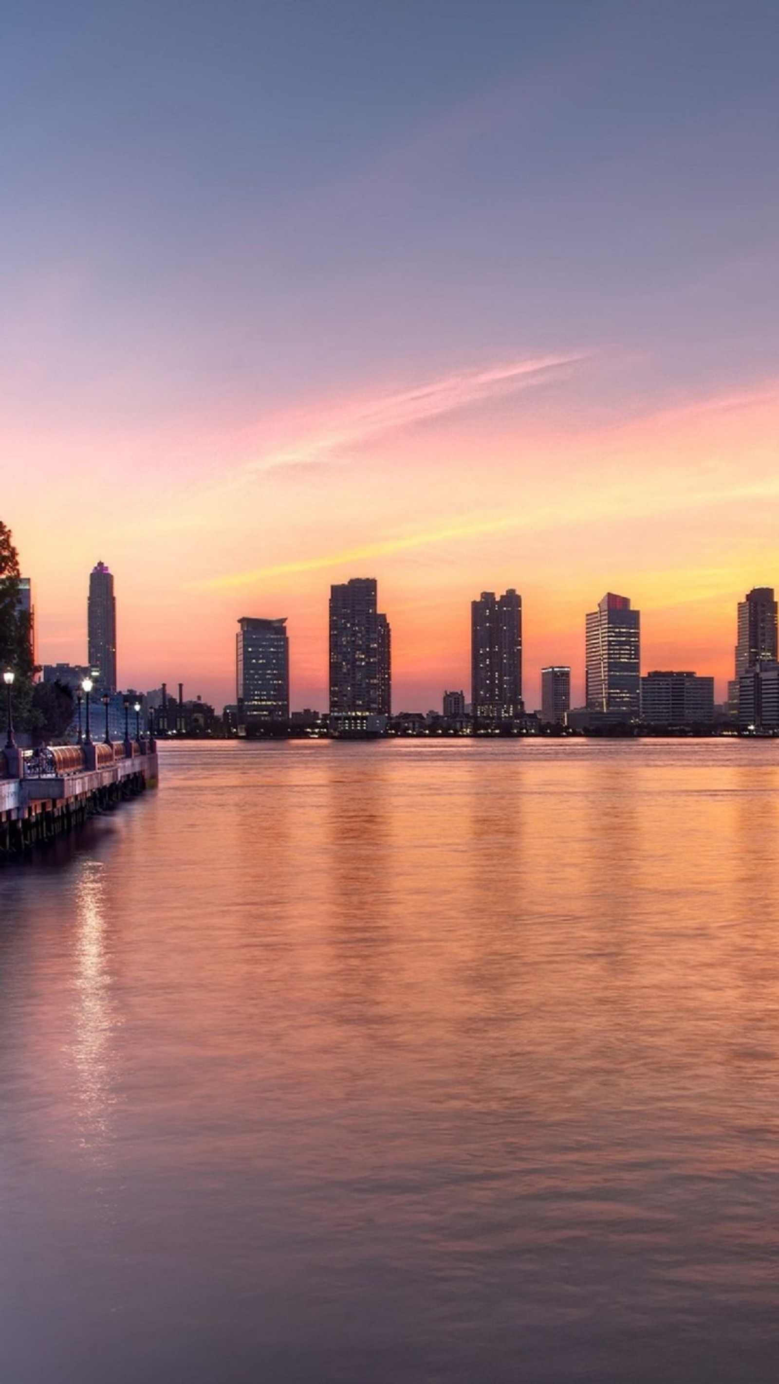 Vista aérea de un horizonte de ciudad al atardecer con un muelle (panorama, paisaje urbano, ciudad, horizonte, crepúsculo)