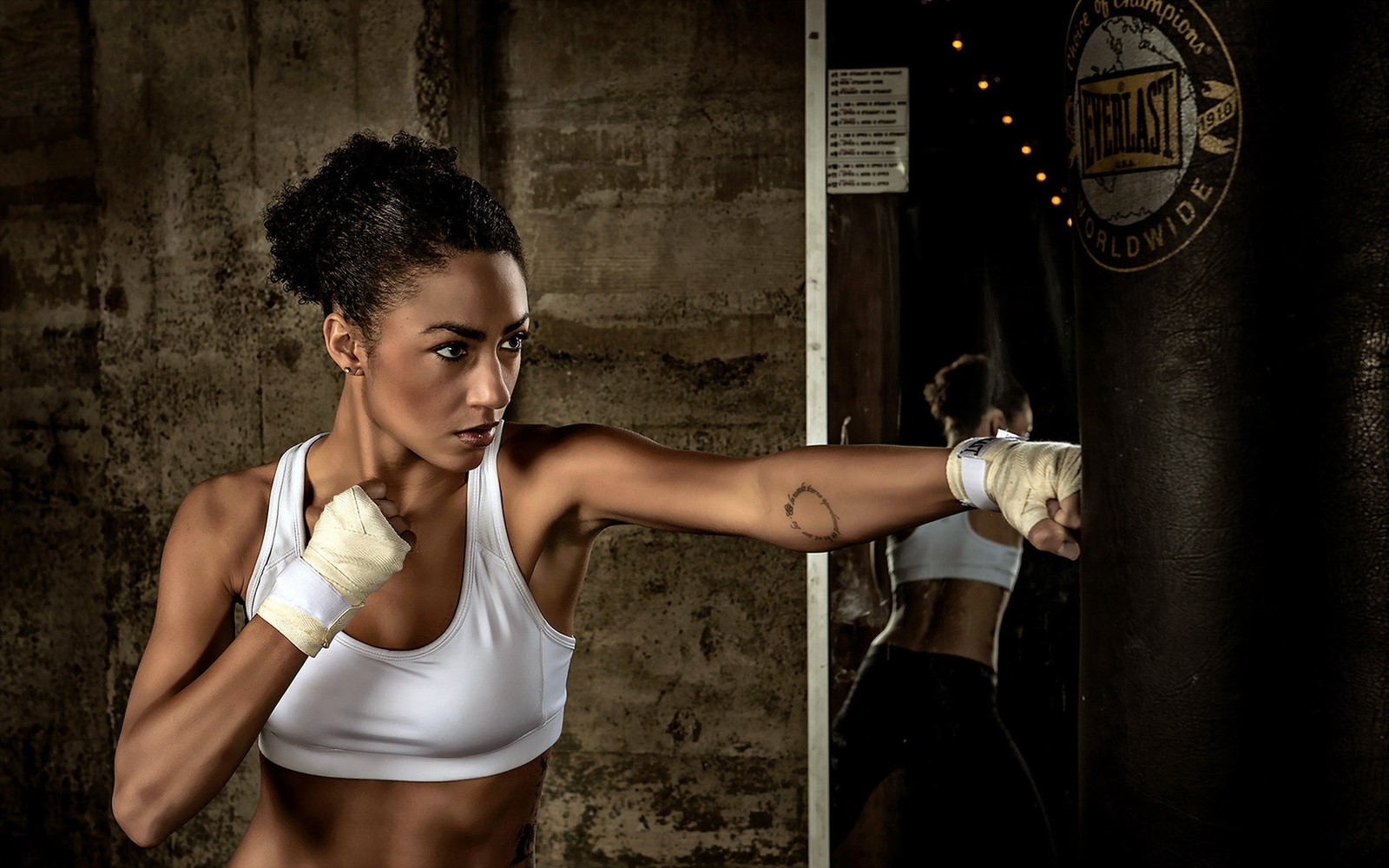 Une femme arabe en haut blanc et shorts blancs faisant de la boxe (épaule, bras, muscle, aptitude physique, modèle)