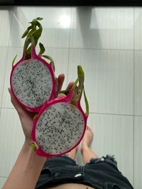 Freshly cut dragon fruit showcasing its vibrant pink skin and speckled white flesh.