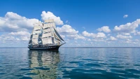 Vaisseau à voiles majestueux glissant sur des eaux calmes sous un ciel vibrant.