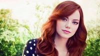 Emma Stone con cabello rojo, mostrando su belleza en un entorno natural al aire libre.