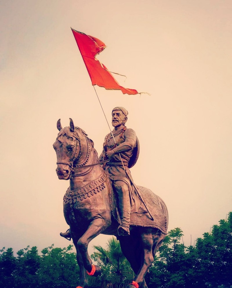 Статуя человека, сидящего на лошади с флагом (шиваджи махарадж, shivaji maharaj, король)