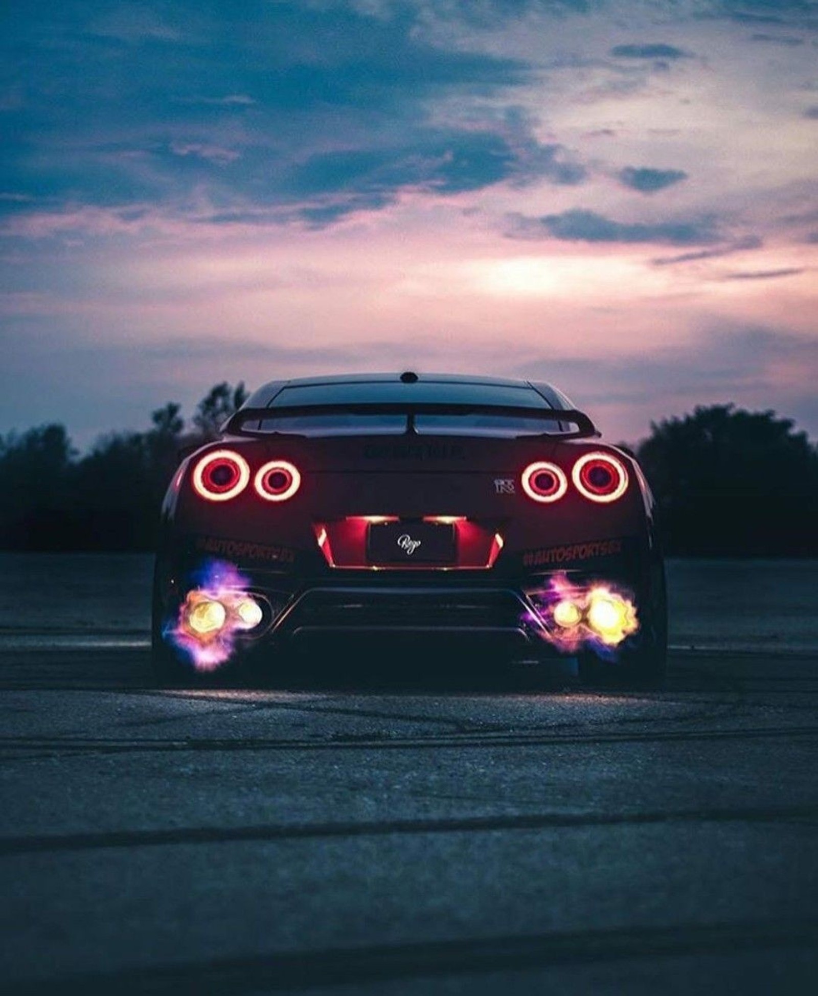 A close up of a red sports car with its lights on (autos, cars, godzila, gtr, nissan)