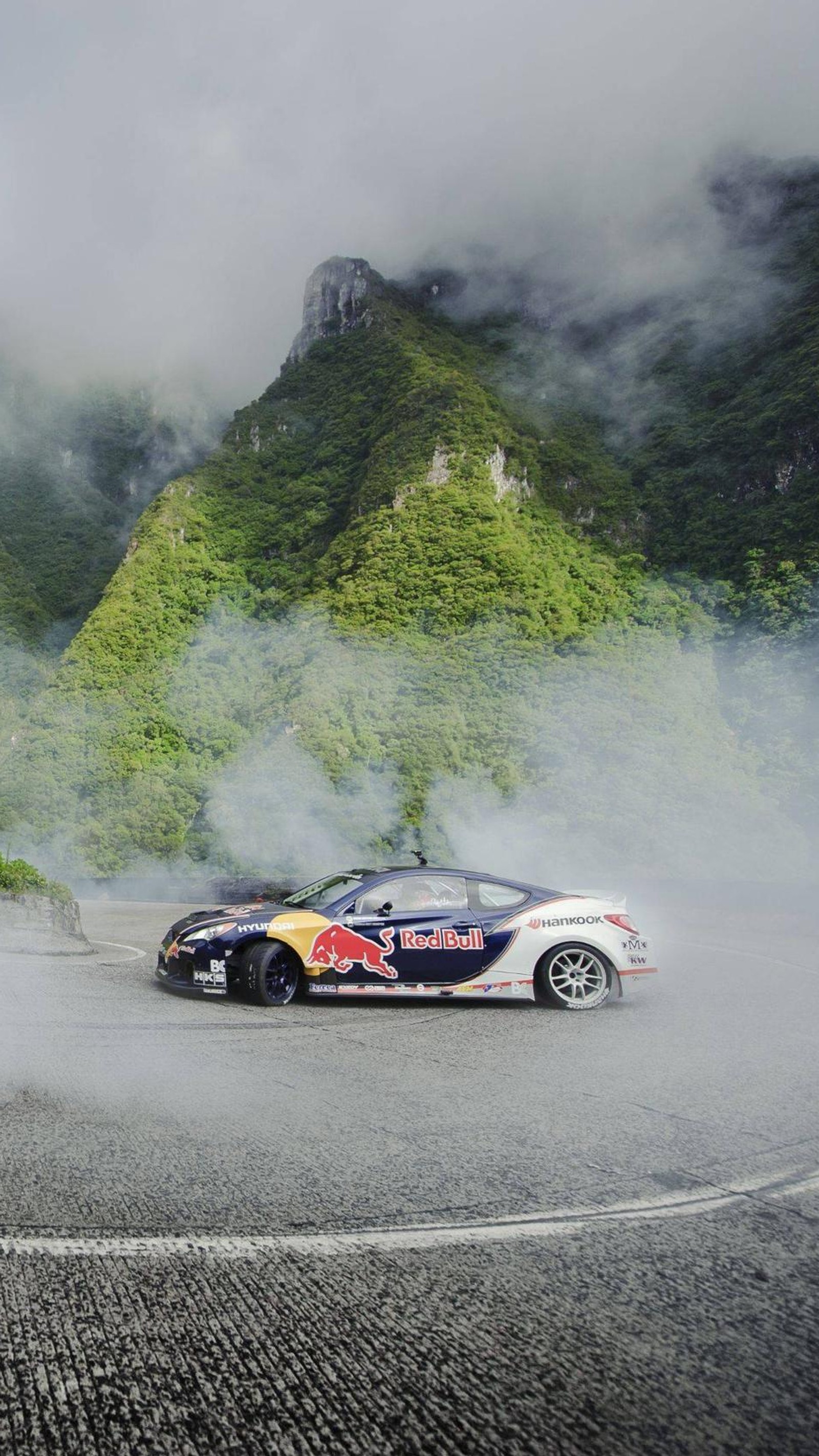 Une voiture enragée roulant sur une route avec de la fumée qui sort (dérive, brume, genèse, hyundai, montagne)