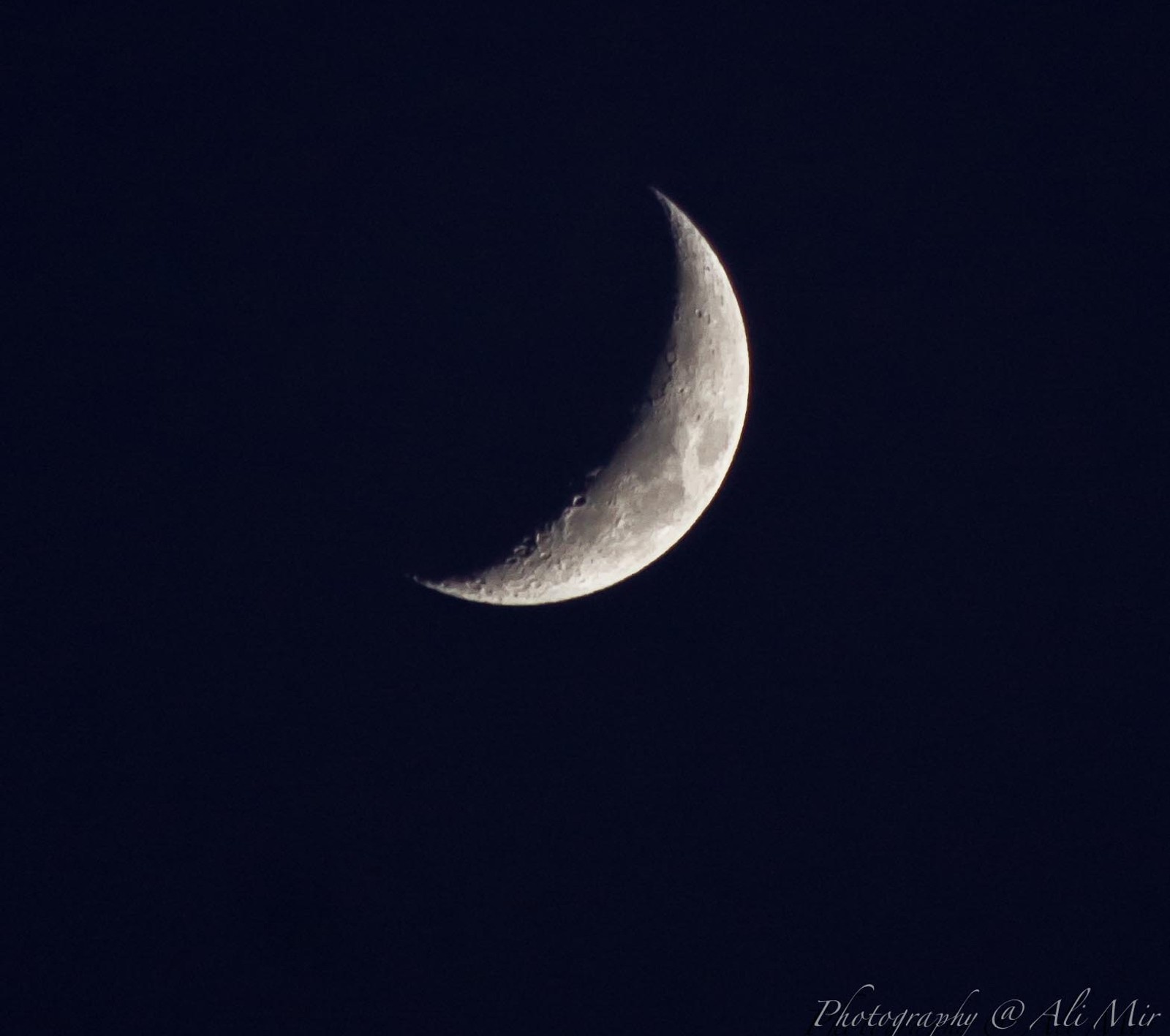 Gros plan d'un croissant dans le ciel noir avec un petit nuage (lune, nuit)