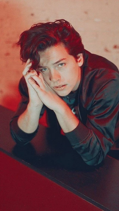 Cole Sprouse en una pose contemplativa con iluminación dramática.