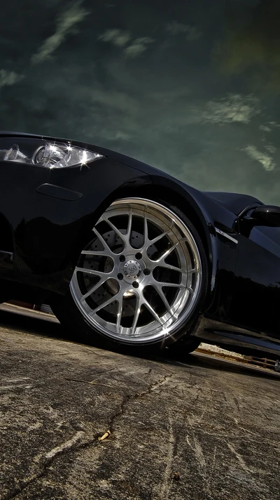 Coche negro elegante con llantas plateadas elegantes contra un cielo dramático