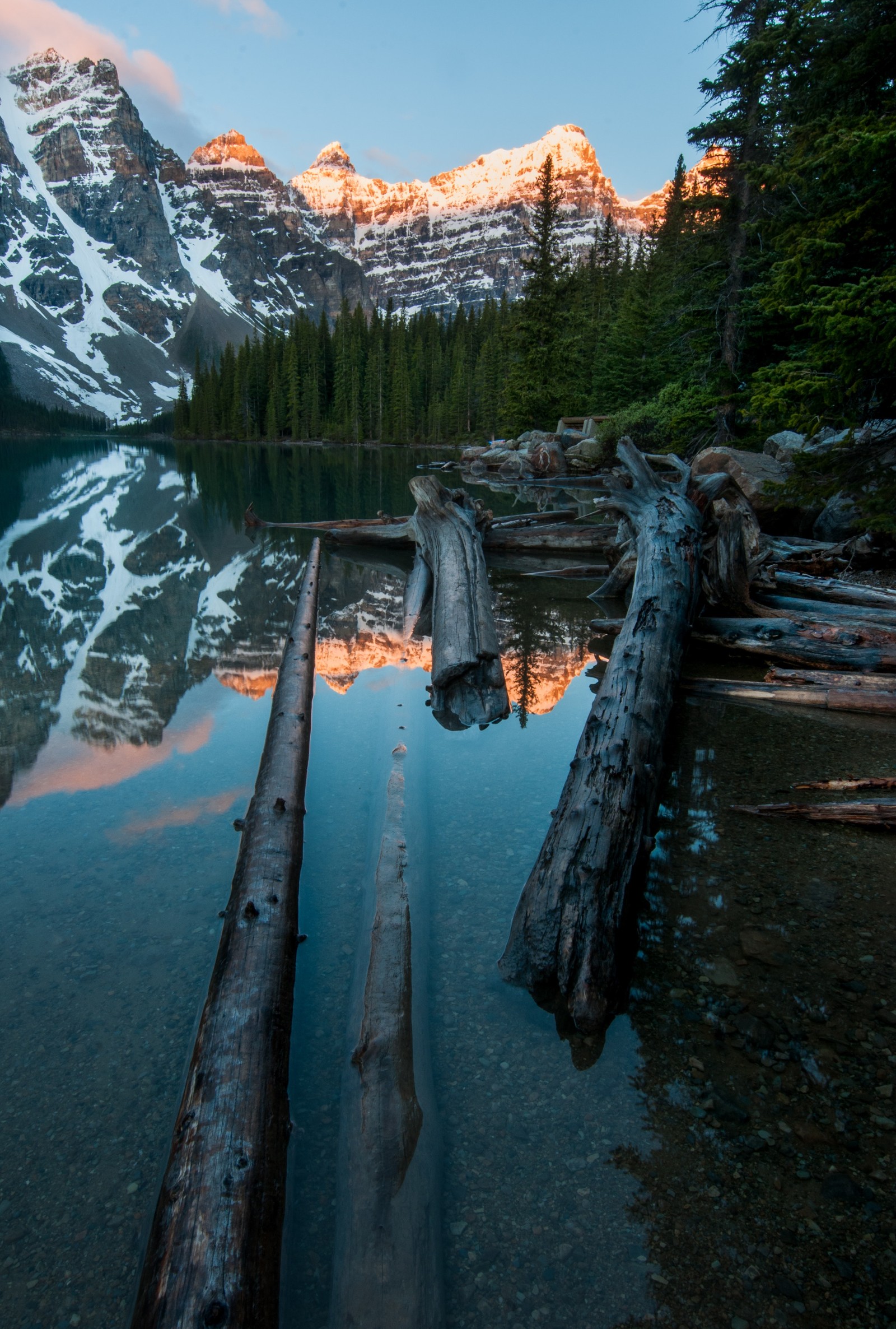 Há uma tora de madeira deitada na margem de um lago. (parque nacional de banff, banff national park, lago moraine, lago bow, bow lake)