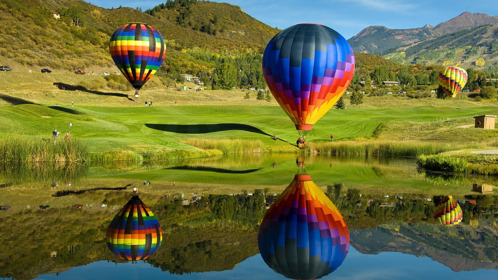 A group of hot air balloons flying over a lake in the mountains (hot air balloon, balloon, hot air ballooning, nature, reflection)