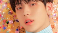 Soobin of Tomorrow X Together surrounded by a colorful, sparkling backdrop.