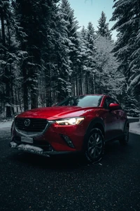 Carro esportivo vermelho Mazda CX-3 em uma paisagem florestal nevada