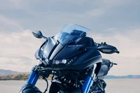 Yamaha-Motorrad, das elegantes Design und fortschrittliche Technik auf der Tokyo Motor Show präsentiert, mit auffälligen Verkleidungen, einer anspruchsvollen Windschutzscheibe und auffälligen blauen Rädern vor einem klaren Himmel.