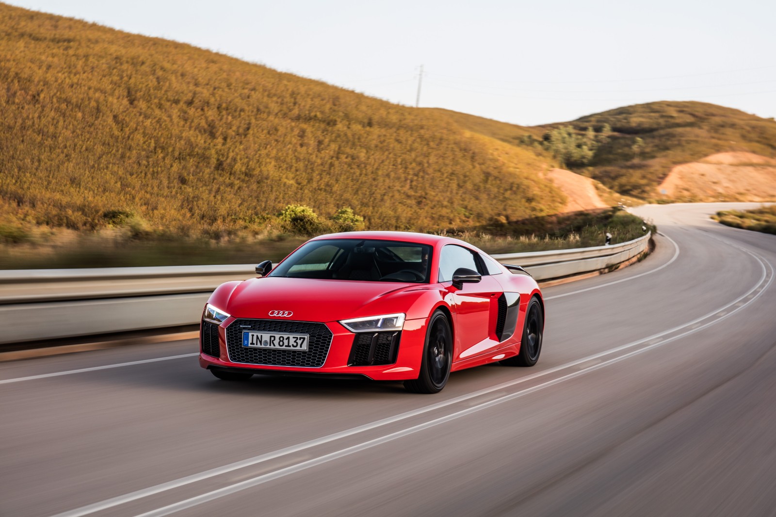 Ein roter audi-sportwagen fährt eine straße in der nähe eines berges entlang (audi, audi r8, auto, sportwagen, v10 motor)