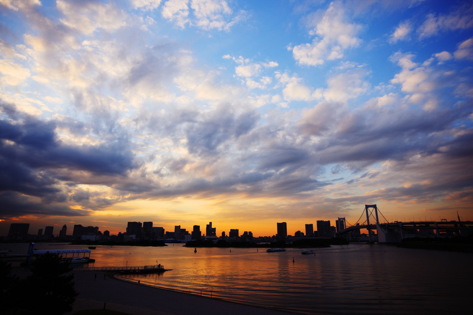 Vista do horizonte da cidade com um rio e barcos na água (por do sol, resplendor, nuvem, horizonte, dia)