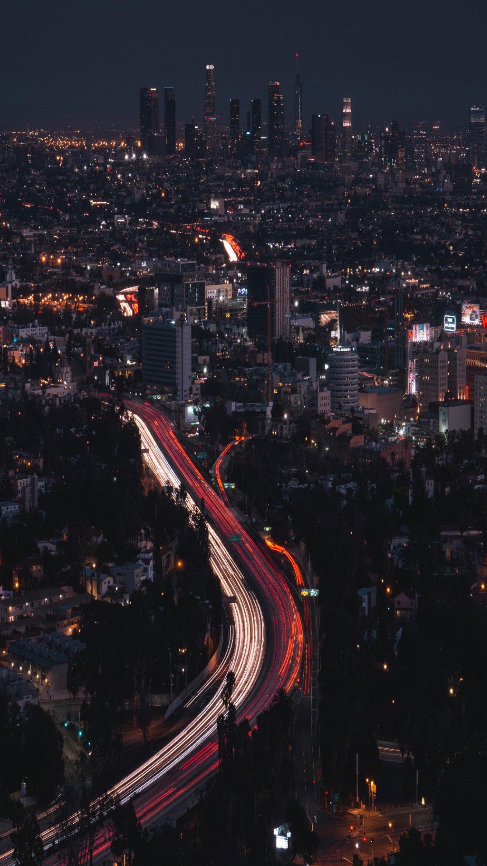 Uma vista aérea de uma cidade à noite com uma rodovia e uma via expressa (cidade, noite, linha do horizonte, viagem)