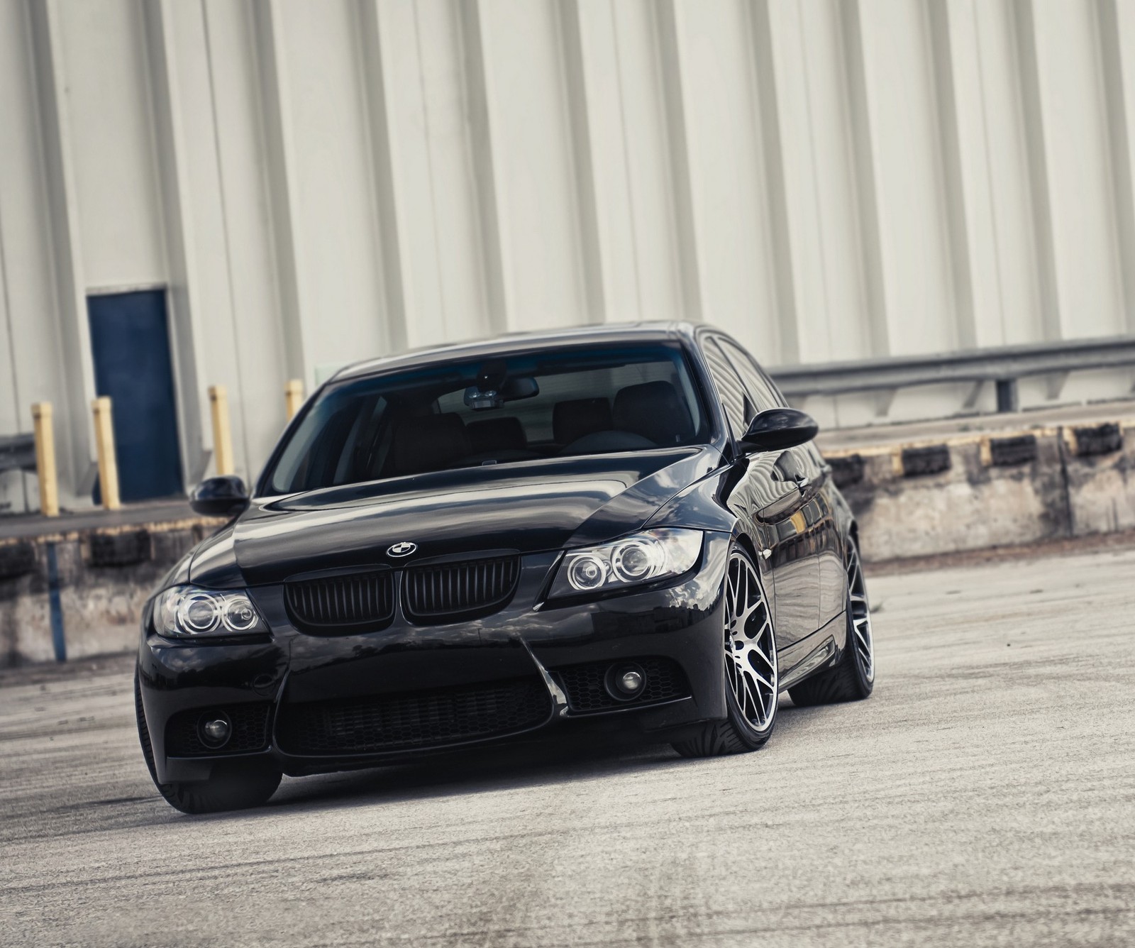 Arafed black bmw car parked in a parking lot with a building in the background (bmw, cars)