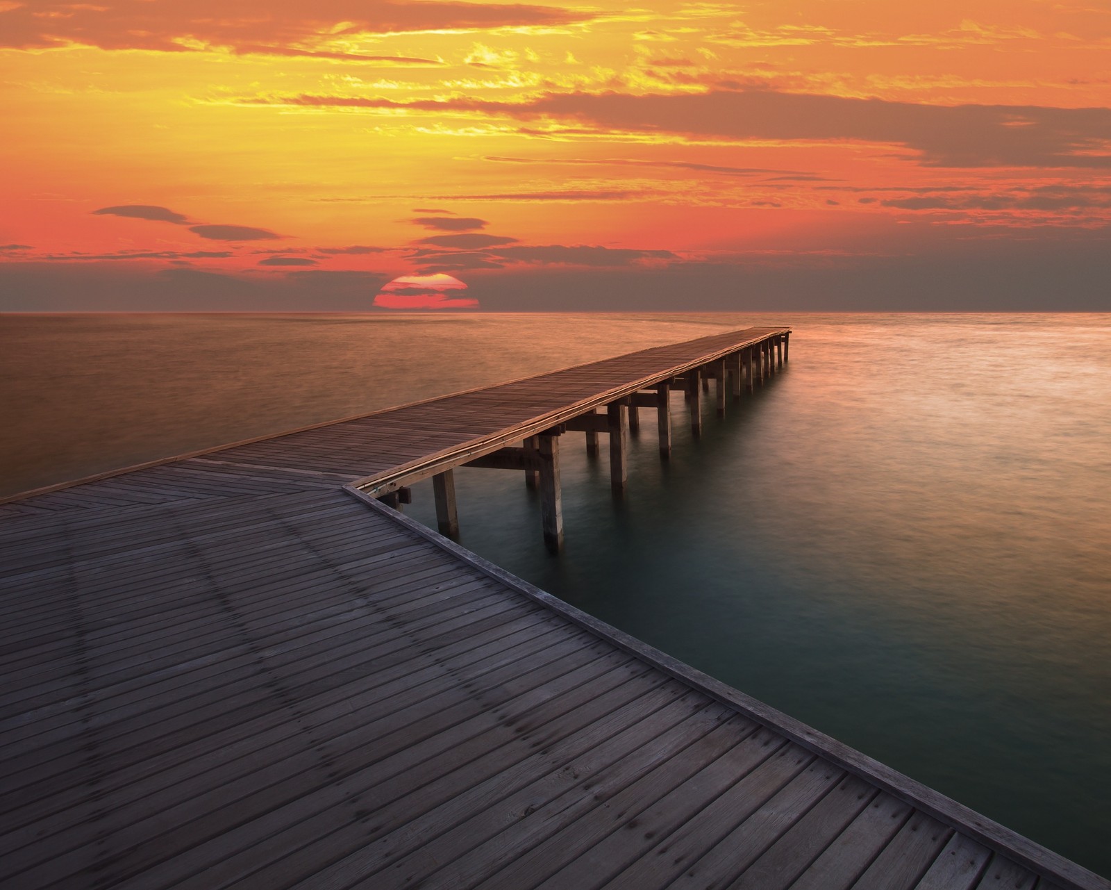 Arafed pier with a sunset in the background and a boat out in the water (beach, bridge, clouds, landscape, ocean)