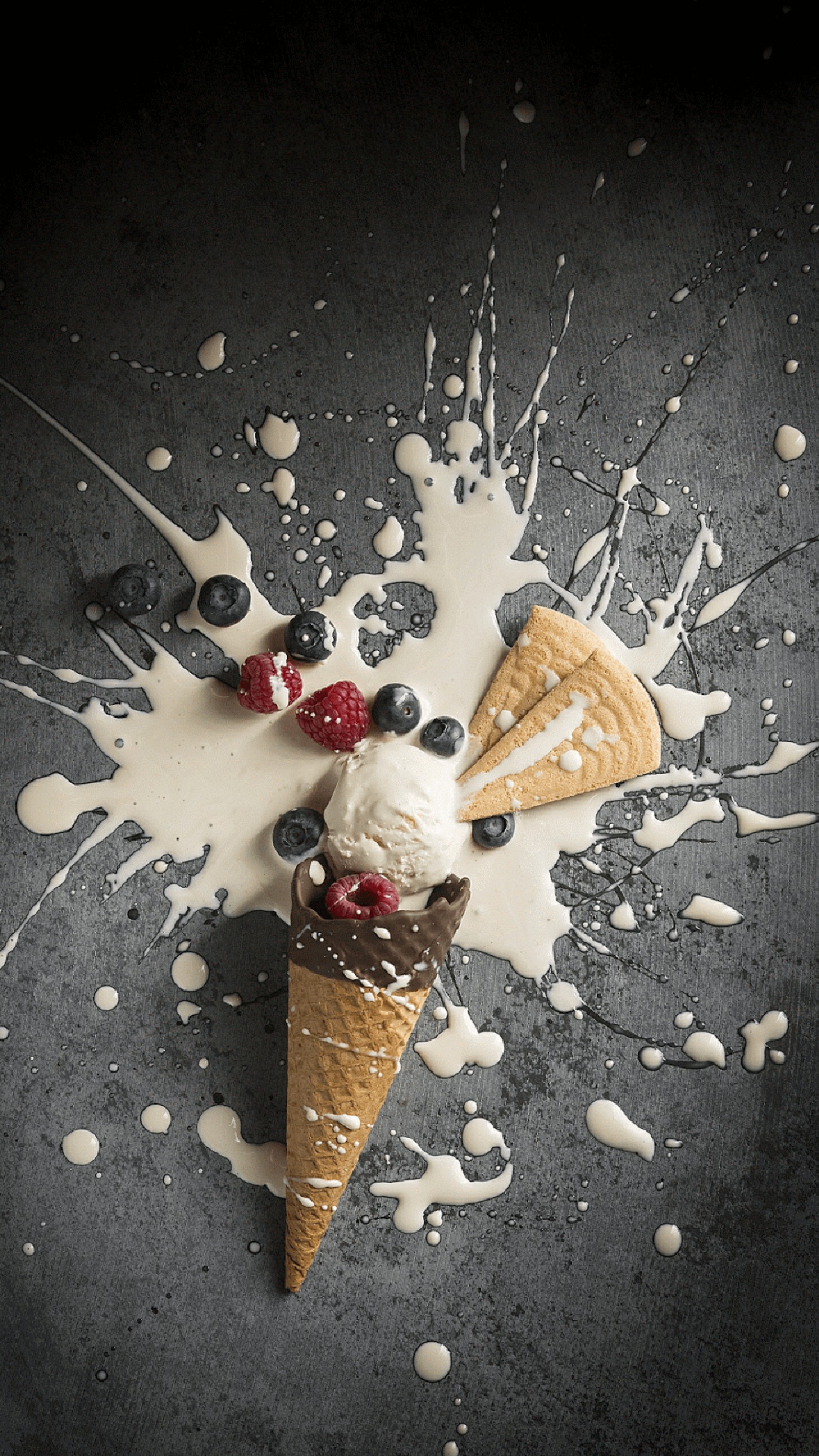 Há um cone de chocolate com sorvete e frutas em cima (biscoito, creme, chão, comida, fruta)