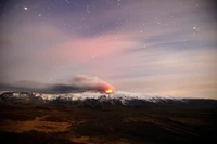 Volcán escudo en erupción por la noche, emitiendo ceniza y lava brillante bajo un cielo estrellado.