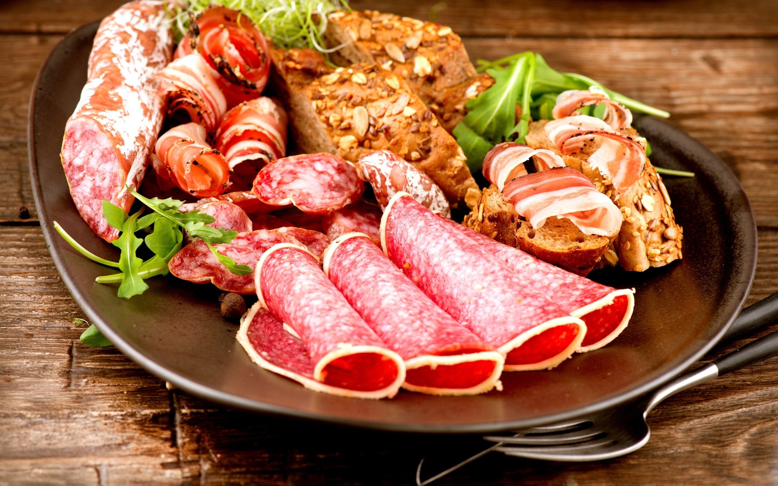 Auf dem tisch liegt ein teller mit fleisch und gemüse (schinken, italienische küche, salami, wurst, essen)