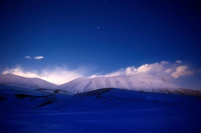 Paisagem de inverno serena: majestosas montanhas cobertas de neve sob um céu estrelado