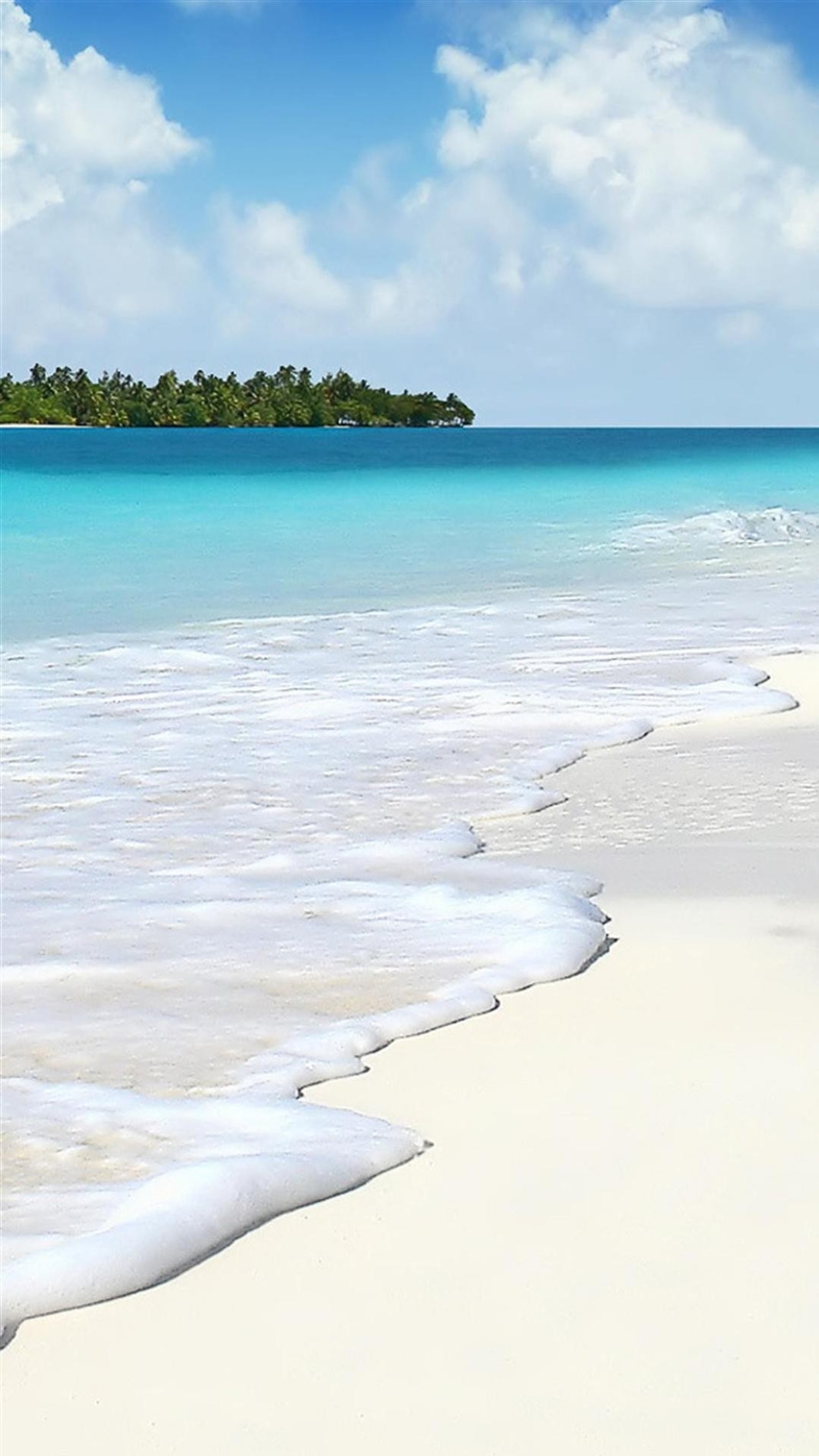 There is a white sand beach with a blue ocean and a small island in the distance (love, nature)