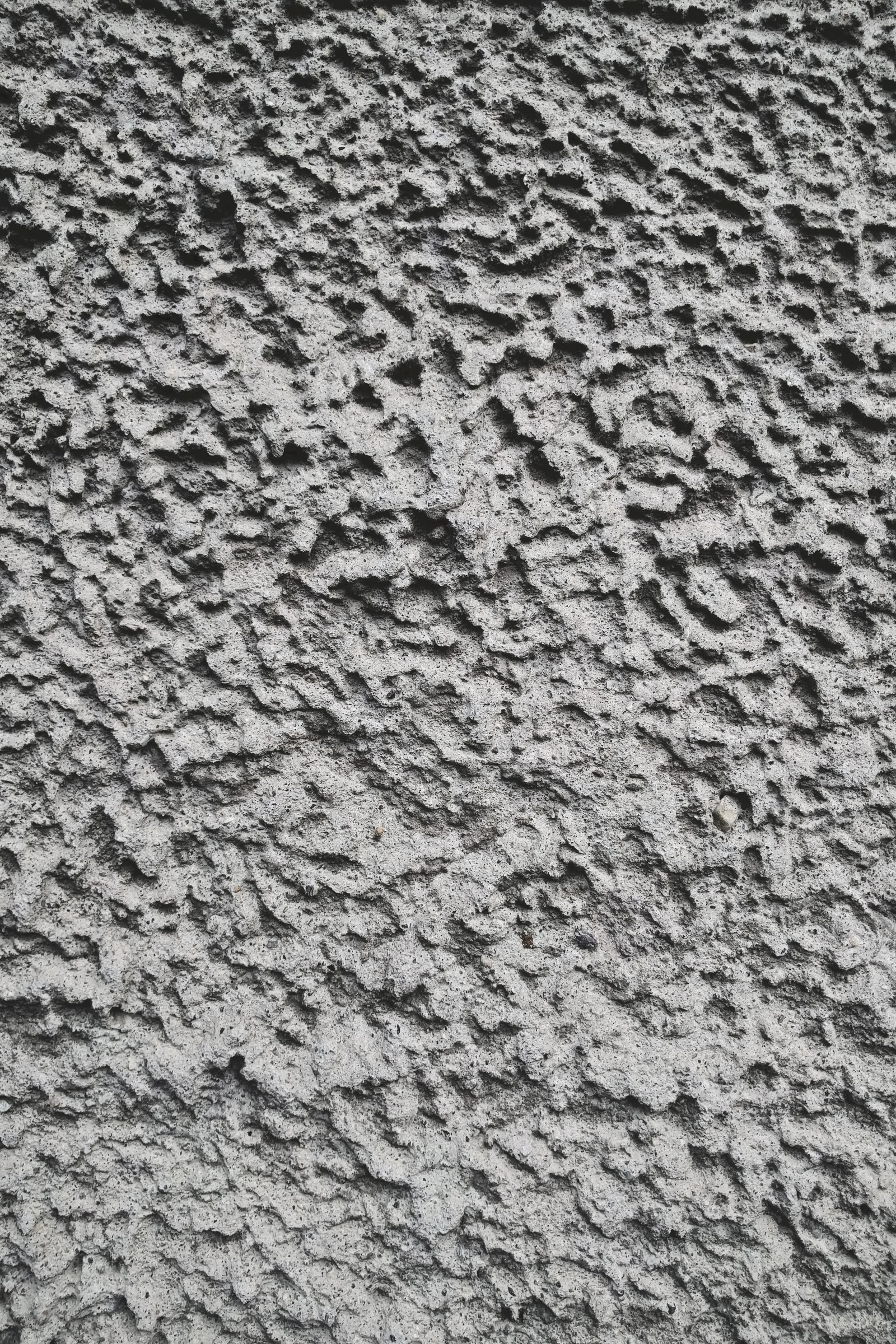 A close up of a black and white photo of a wall (bumps, concrete, grey, twotone, wall)