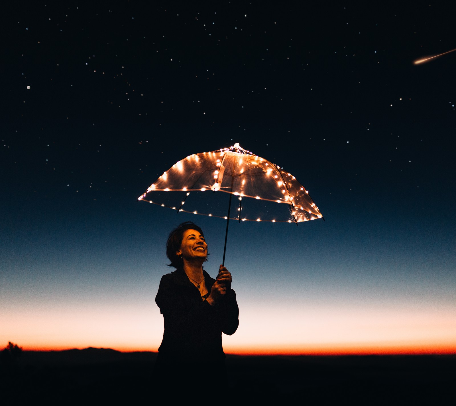 Una mujer sosteniendo un paraguas con luces en la oscuridad (1080, hermoso, negro, azul, genial)