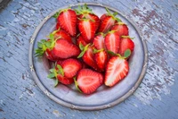 Freshly sliced strawberries arranged on a rustic plate.