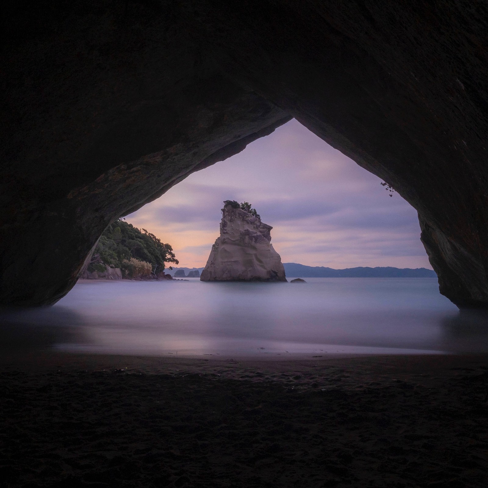 Une vue d'une grotte avec une roche qui en sort (formation, roche, nature, mer, arc naturel)