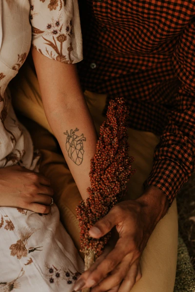 Intertwined Hands with a Heart Tattoo and Natural Elements