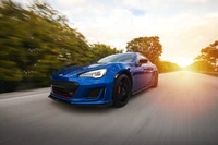 Dynamic Subaru BRZ in motion against a vibrant sunset backdrop.