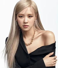 Retrato elegante de un cantante de K-pop con cabello largo y rubio platino, vistiendo un blazer negro y un collar de cadena dorada.