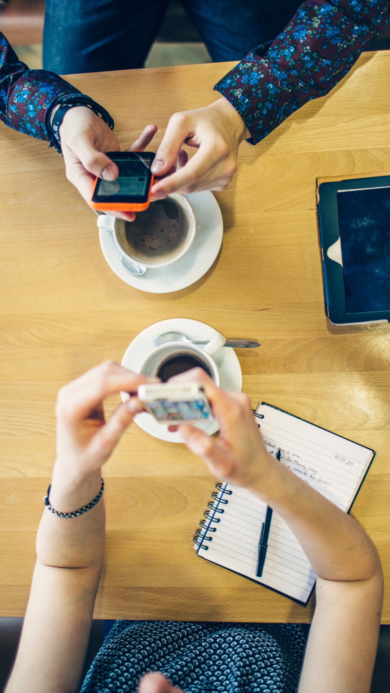 Personas sentadas en una mesa con sus teléfonos móviles y una taza de café (café, gente, tecnología)