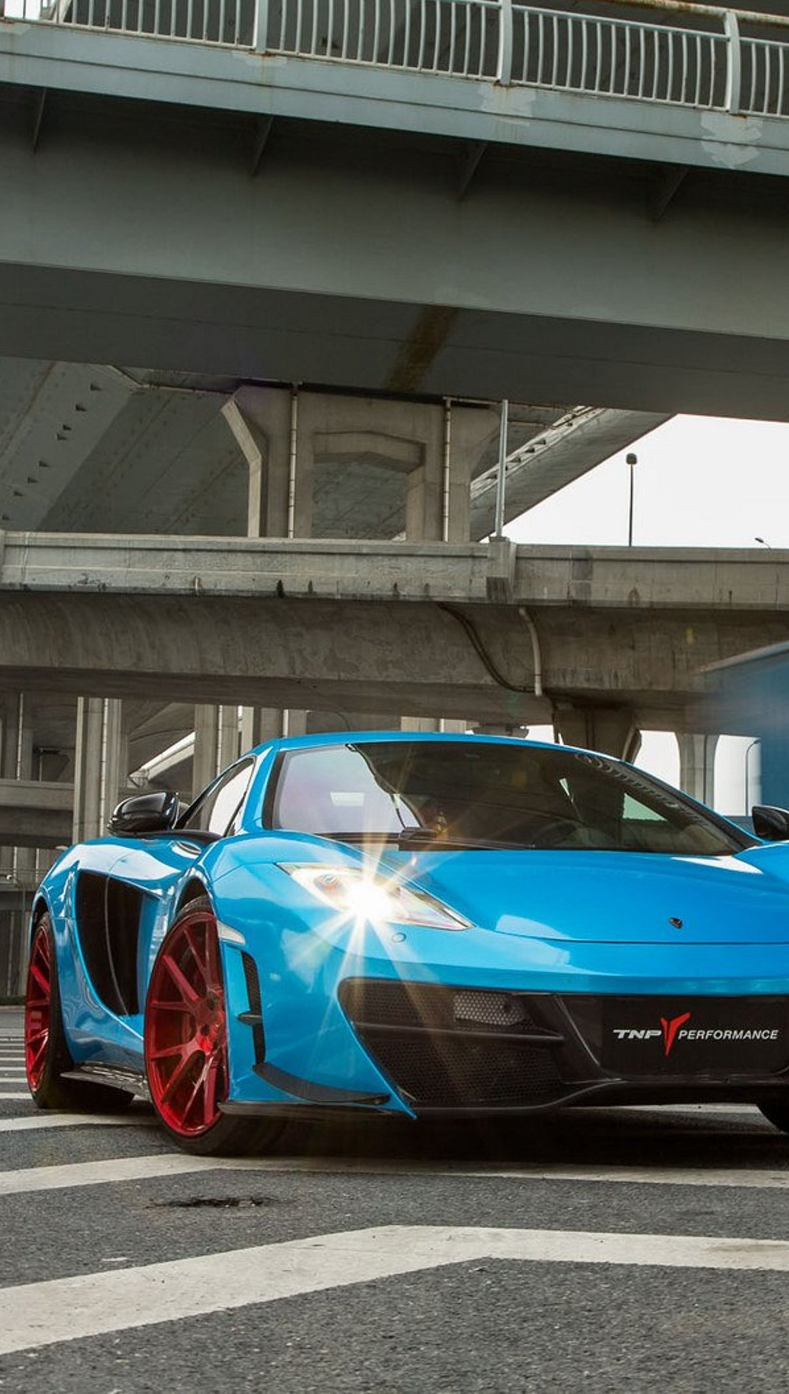 Arafed blue sports car parked under a bridge on a city street (blue, car, mclaren mp4, road)