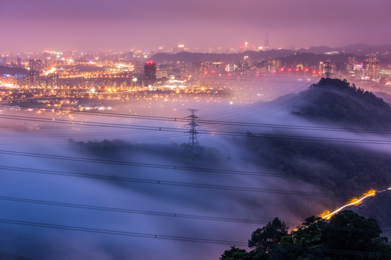 Arafed view of a city with a foggy mountain and power lines (fog, city, cityscape, horizon, mist)