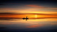 Silhouette d'un voilier au coucher du soleil, reflétant des teintes calmes sur la mer tranquille.