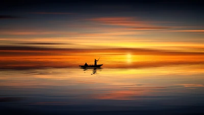 Silueta de un velero al atardecer, reflejando tonos calmados en el mar tranquilo.