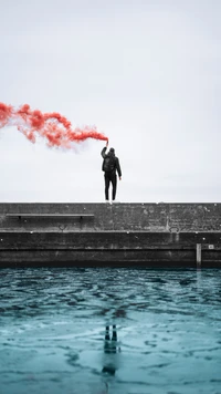 Red Smoke Against a Serene Water and Cloudy Sunset