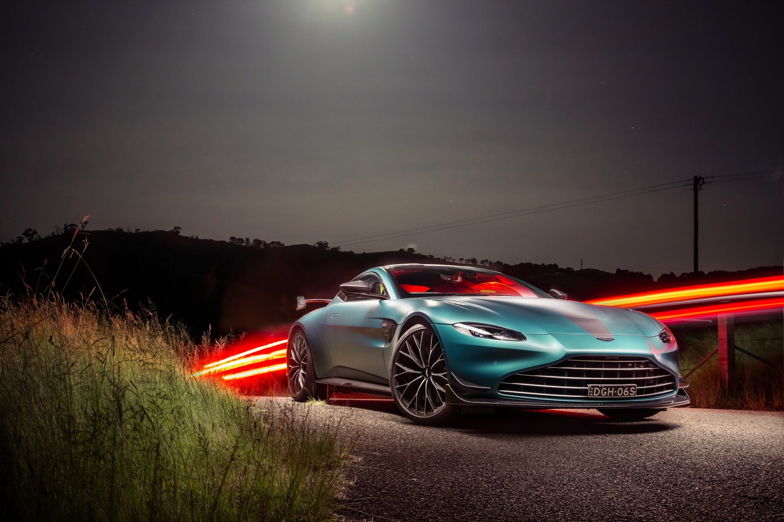 Une voiture de sport bleue roulant sur une route la nuit (aston martin vantage, racing green, édition f1, voitures, fond décran 4k)