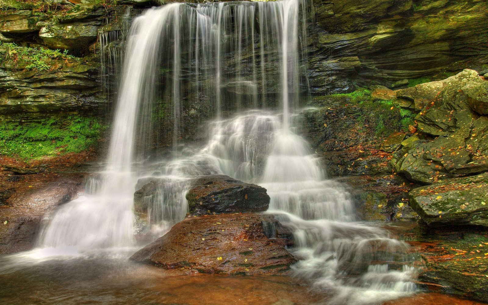 Um close em uma cachoeira com uma pedra em primeiro plano (cachoeira, corpo de água, recursos hídricos, natureza, água)