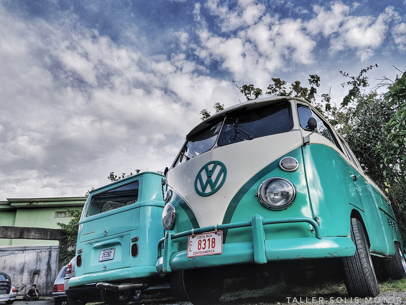 There is a vw bus parked in a parking lot with a van behind it (bus, vw)