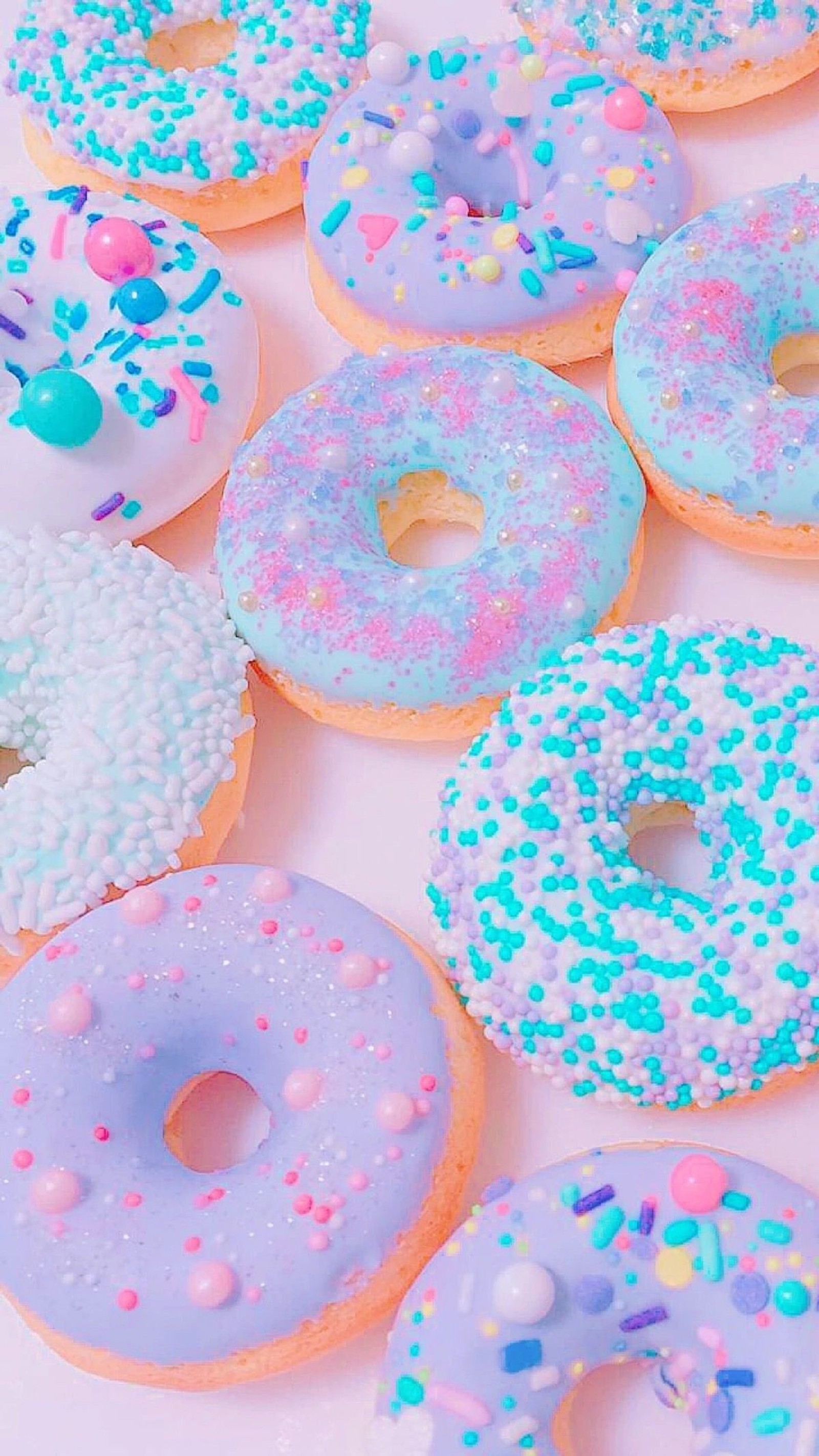 Um close em uma mesa com um monte de donuts em cima (unicórnio, açúcar, comida, rosa, pastel)