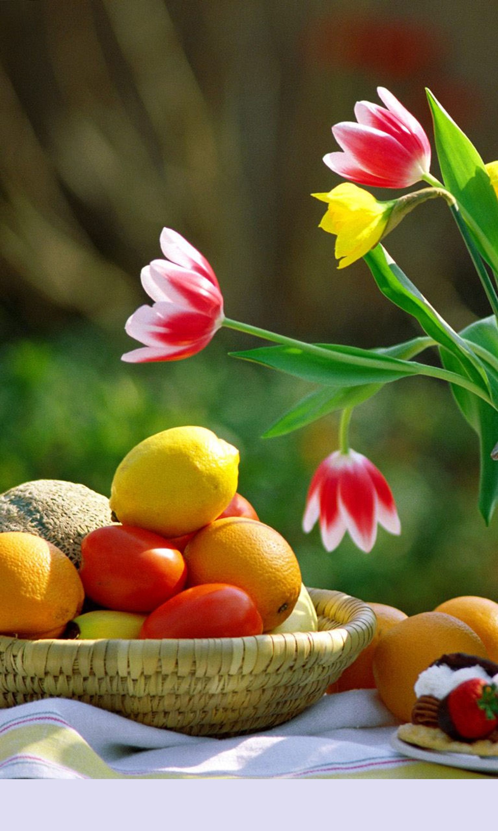 Auf einem tisch ist ein korb mit obst und blumen (blumen, frühling)