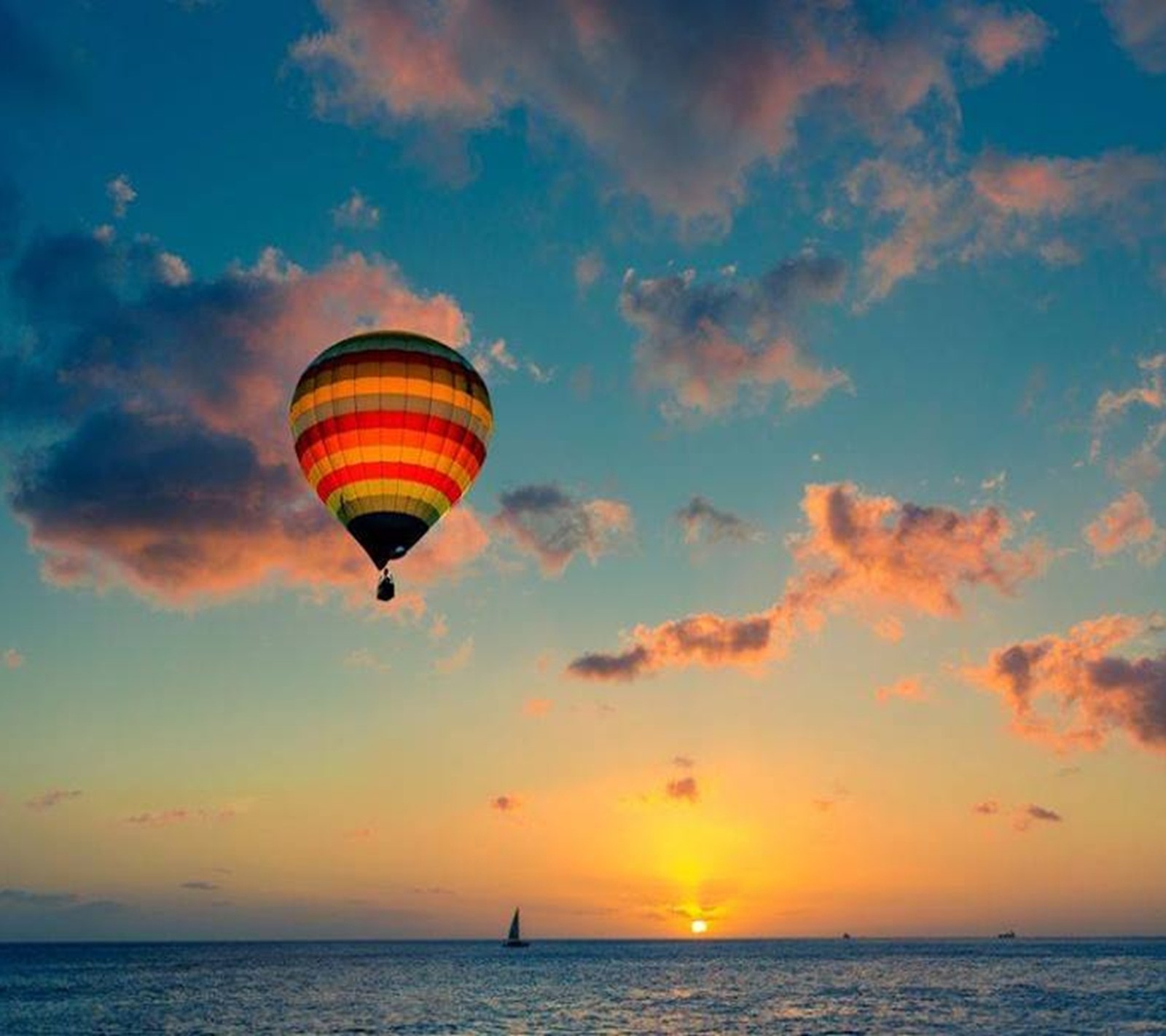 Un globo de aire caliente volando sobre el océano al atardecer (globos, on air)