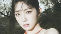 Irene from Red Velvet in a captivating close-up, featuring a serene expression amidst a natural backdrop.